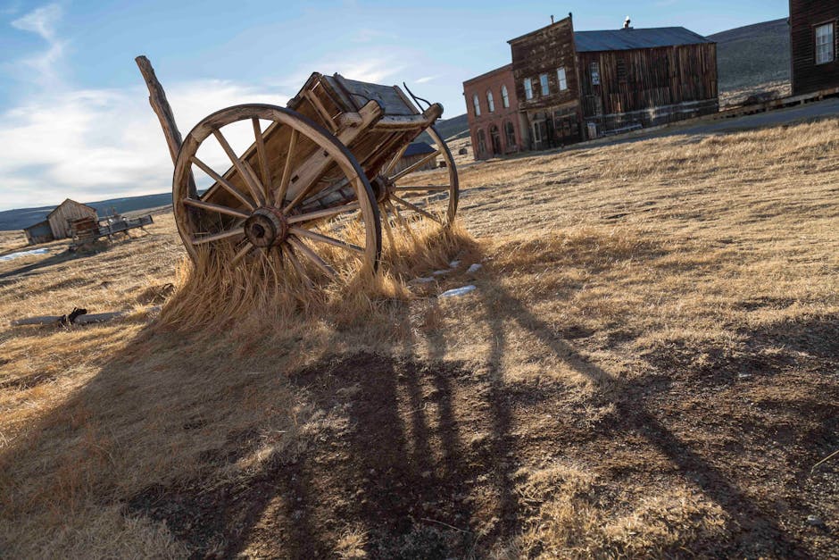 Rustic wooden wagon in an abandoned ghost town under clear blue skies.