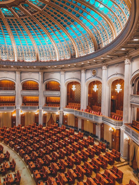 Majestic view of an ornate parliamentary chamber with a striking turquoise dome and plush seating.